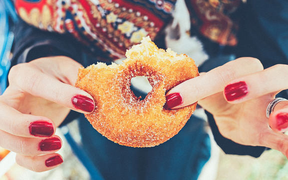Bilde av hender som holder en halvspist donut med sukker på