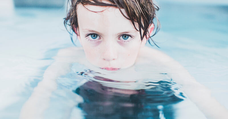 Bilde av gutt i basseng med alvorlig blikk