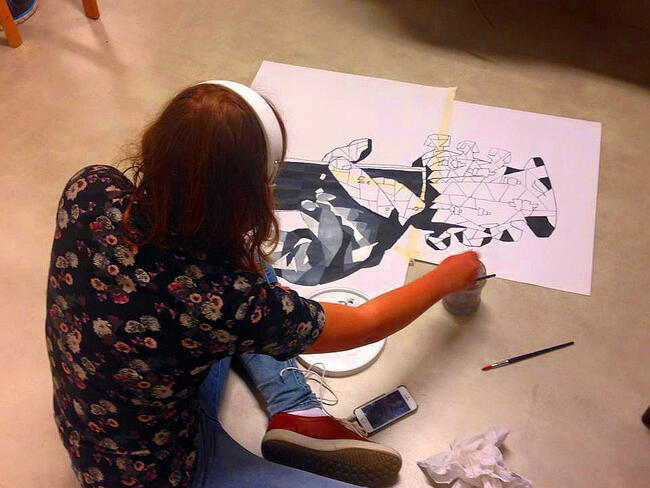 jente sit og maler på eit ark på gulvet