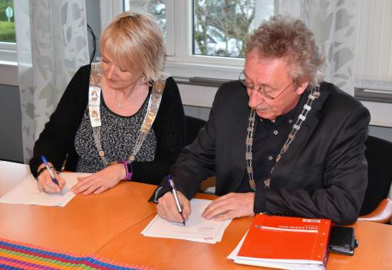 Ordførar Wenche Tislevoll og Harry Herstad signerer avtale om kommunesamanslåging