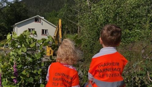 To barn ser på gravemaskin