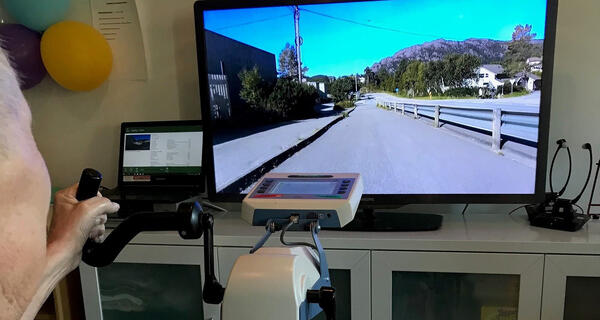 mann syklar ergometersykkel og ser på tv - foto