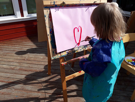 Et barn som maler et hjerte utendørs