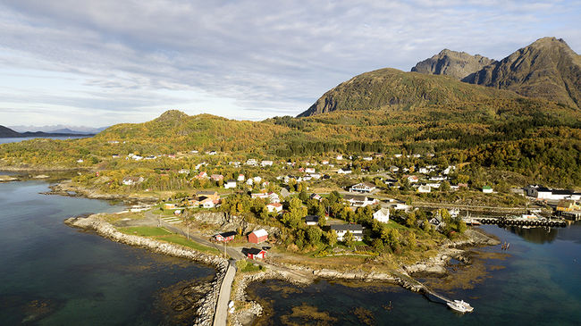 Dronefoto over bygda skutvik: havn, hus og fjell