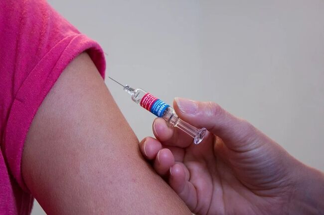 Illustrasjonsbilde av en sprøyte som skal settes inn i arm like før vaksinering