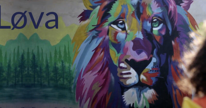 Bilde av en person foran en sto, fargerik grafitti av en løve