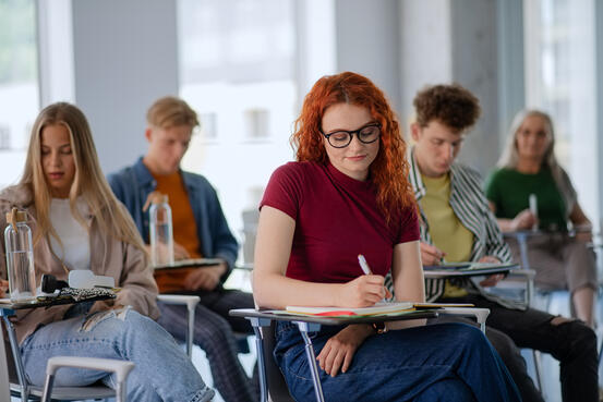 Portrait of group of university students sitting in classroom indoors, studying.