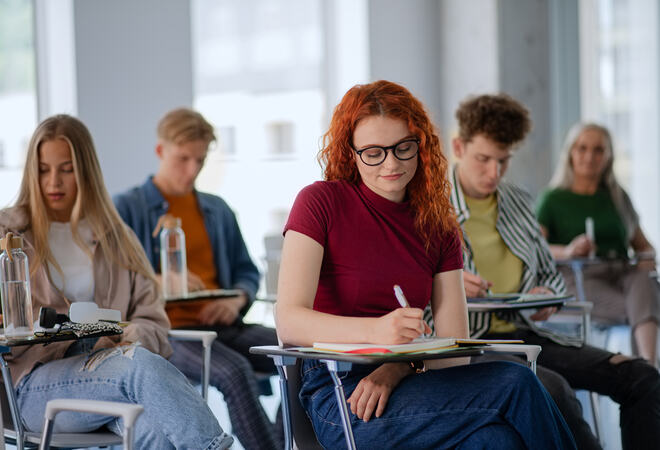 Portrait of group of university students sitting in classroom indoors, studying.