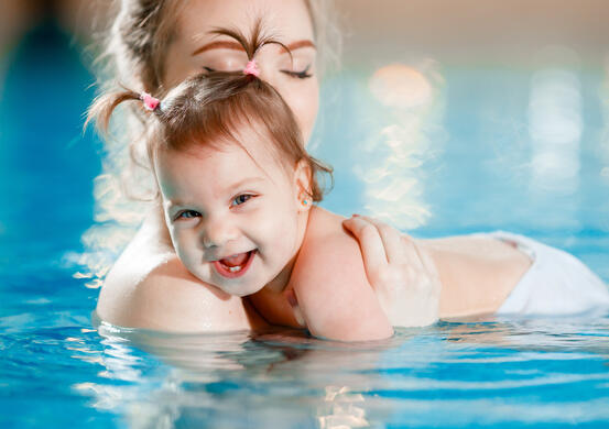 Mom and baby swim in the pool.
