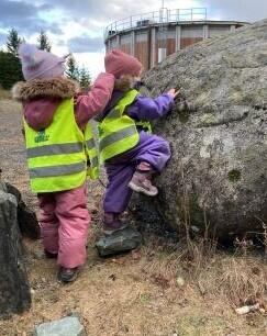 To barn klatrer på stor stein