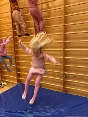 Barn hopper fra ribbevegg i gymsal