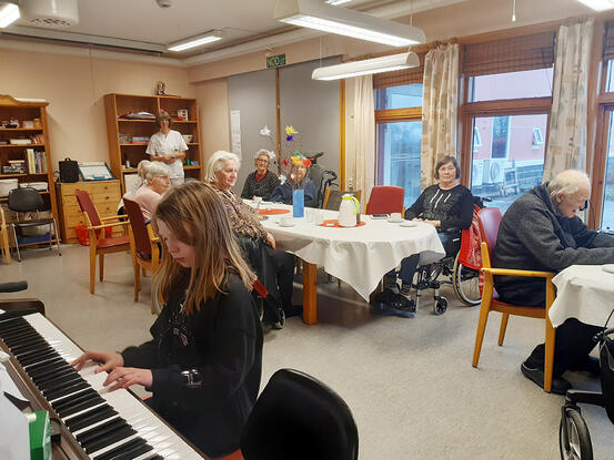 Jente spiller piano på Hamarøy Bygdeheim