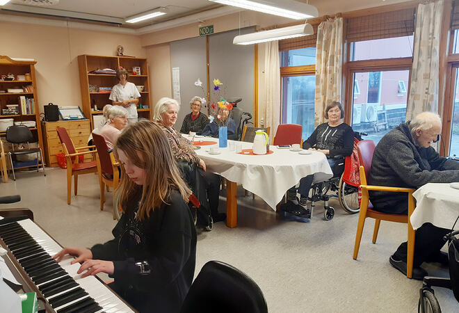 Jente spiller piano på Hamarøy Bygdeheim