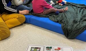 barn sit på madrass saman med vaksen. foto