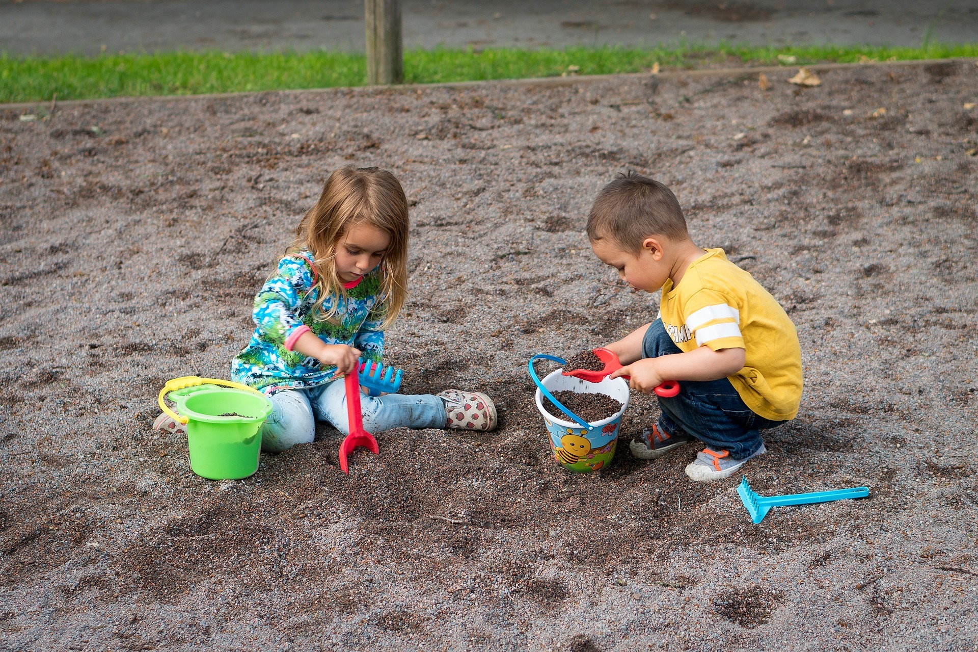 2 barn leikar i sanden med spade og bøtte