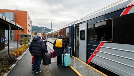 Tog med passasjerer på en jernbanestasjon