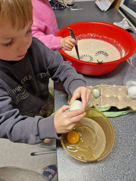 Barn kakker egg for å helle opp i pannekakerøre