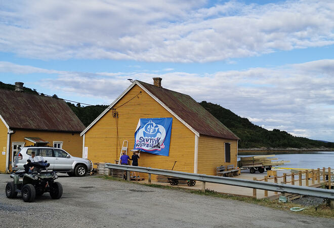 Folk monterer banner Skutvik kystfestival