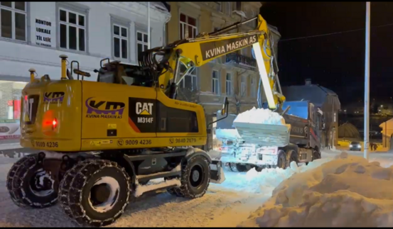 bilde viser gravemaskin som løfter snø over på et lasteplan