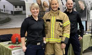 tre personar på stand, ei dame i uniform, ei dame i brannutrykningsdress, og ein mann i uniform for brann og redning.