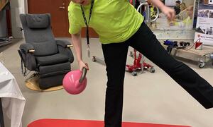 jente står på balansepute og held ei vektball