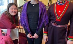 Tre jentene står i salen, to har samisk klær på seg
