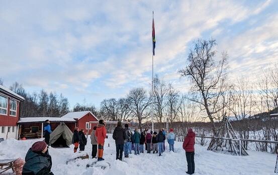 Voksne og elever deltar på flaggheising på Hamarøy Montessoriskole