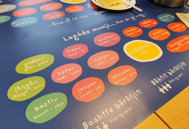 Blå plastik matte på spisebored med ord på lulesamisk og norsk