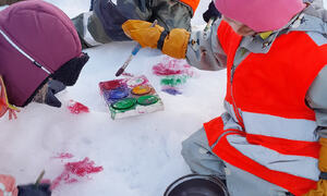 Barn med vinterklær og refleksvest maler snø med vannfarger