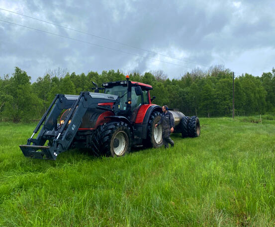 Stor traktor på marka og mann står ved siden av det