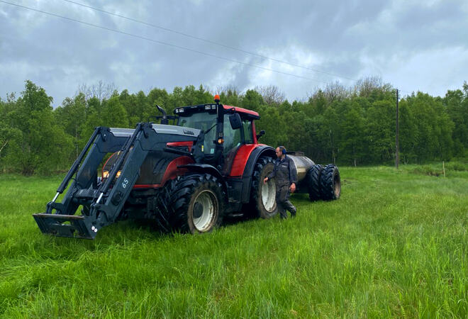 Stor traktor på marka og mann står ved siden av det