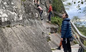 Barn klatrer på fjell, voksen passer på