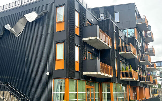 Bildet syner den utvendige fasaden til Leirvikstova som er i svart og oransje.
