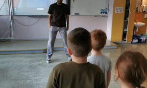 En mann lærer tre elever på skole til å danse BlimE dans