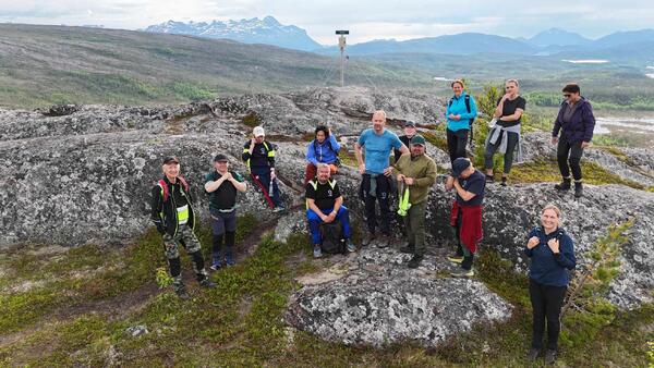 12 mennesker i turklær står på toppen av fjell