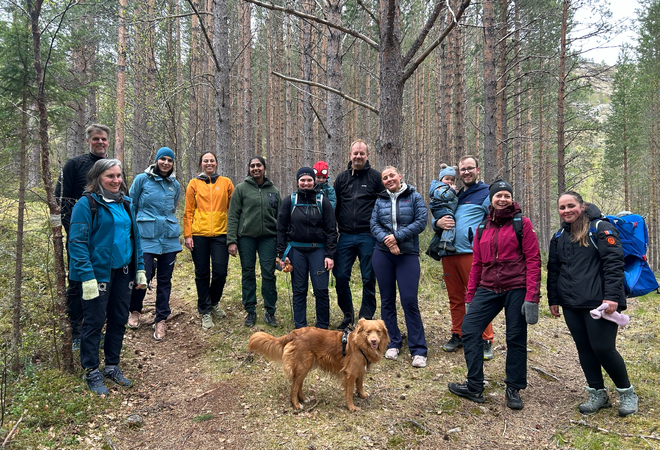 Masse folk i turklær med barn og hund står i skogen