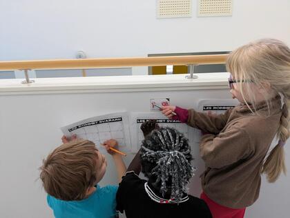 Tre elever sjekker bokstaver på veggen