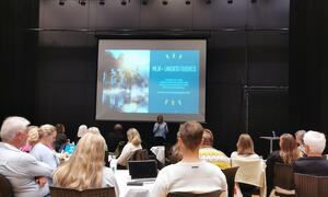 Masse folk sitter i salen og ser på presentasjon