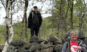 Gruppe turgåere hviler blant steinete terreng og bjørketrær. Noen bruker røde vester