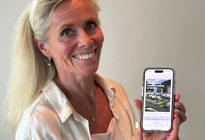 ei dame viser fram telefonen sin der den nye nettsida viser