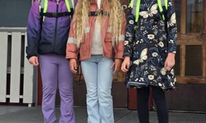 Tre jenter står på trappe med skolesekk