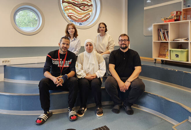 Tre kvinner og to menn sitter på trappe på barnerom