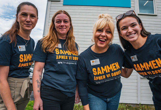 Fire kviner står og smiler, logo til Hamarøy kommune bak på veggen