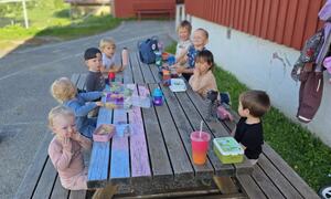 Barnehagen som spiser frokost ute på benkene i nydelig vær