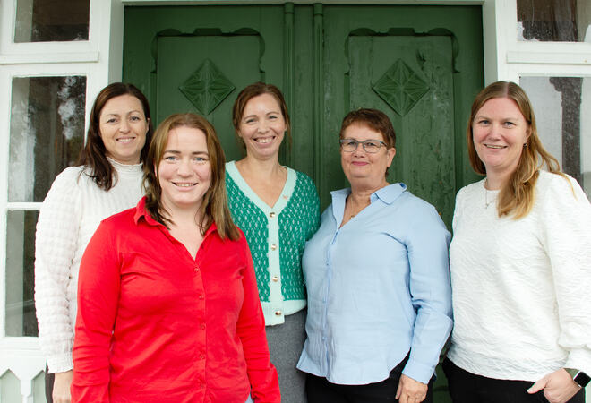 Fem kvinner står ute ved grønn dør