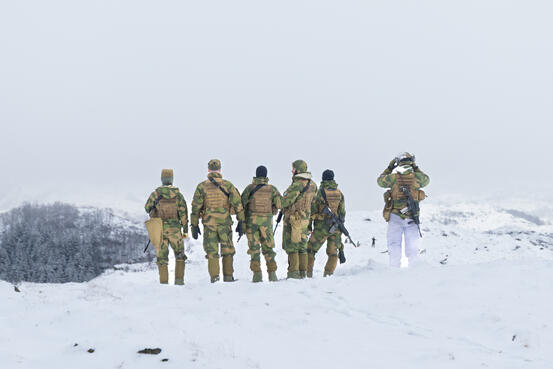 Marktørtjeneste i felt. Foto: Forsvaret/ Nora Elisabeth Madell 6 seks soldater står ute i feltet og speider mot horisonten. De er markører i felt.