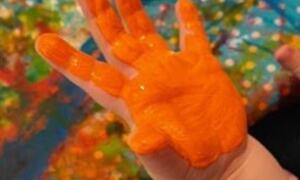 Bildet viser maling med oansje farge på barnehånd