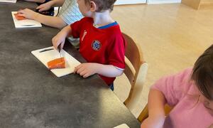 Bildet viser barnehagebarn som skjærer laks