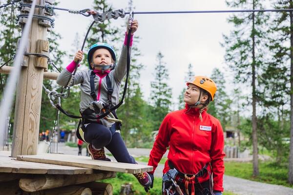 Barn i klatrepark får veiledning av voksen fra Røde kors