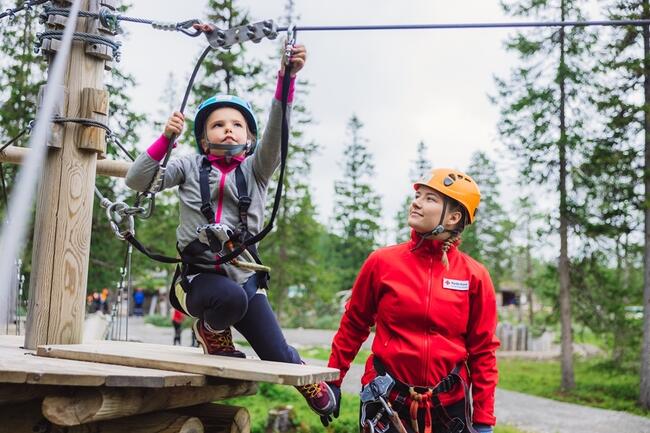 Barn i klatrepark får veiledning av voksen fra Røde kors